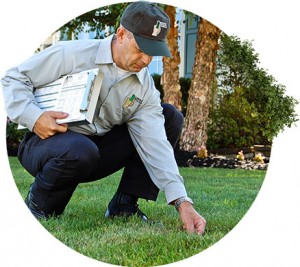 Lawn Doctor expert with clipboard stoops down to provide Lawn Maintenance in Cape Cod